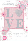 The image shows a beautifully styled anniversary card whose gentle colour story of pastel pinks and silvery greys would feel perfectly at home on a Bromley Common mantelpiece. At its centre, the word LOVE is written in generous, raised letters, each one softly coated with fine glitter so that they glimmer like tiny lights when tilted toward a window. The texture of these letters is pronounced yet refined, offering a pleasing contrast to the smooth card beneath-similar to the way textured petals stand out in a carefully layered anniversary bouquet. Around the central word, an array of illustrated blossoms unfurls: delicate flowers in blush and mauve, accompanied by slender leaves and curling vines. The blooms appear almost watercolor-soft, with gentle gradients of colour that bleed from pale pink into near white, echoing real petals just as they open. Fine outlines in grey and hints of silver foil lend structure and a subtle sparkle, like morning dew on foliage. The floral pattern sweeps diagonally across the card, giving a sense of light movement, as though a breeze were passing through an arrangement displayed in a Bromley Common living room. The background is a warm, milky pink that softens toward the centre, providing a tender, romantic backdrop. Above and within the design, elegant script phrases-such as On Our Anniversary and I love you today and always-are printed in understated grey, blending seamlessly with the colour palette rather than overpowering it. The result is a card that feels as intimate and thoughtful as a hand-delivered bouquet to a BR2 doorstep, capturing the quiet joy of marking another year side by side.